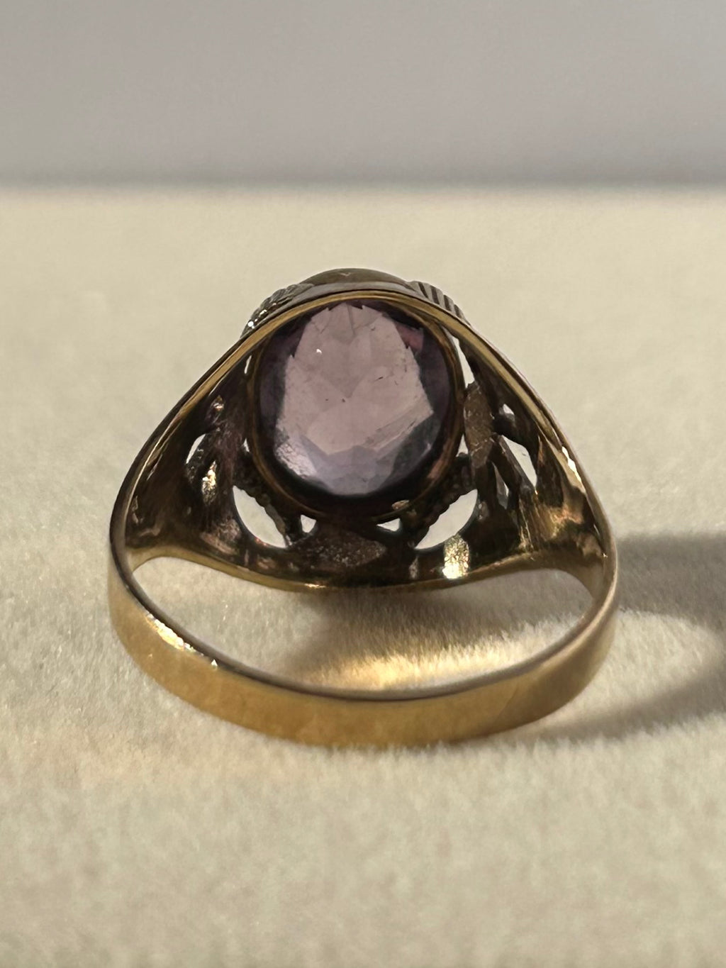 Anillo vintage de amatista en oro de 8 quilates con piedra de corte ovalado y hombros calados.