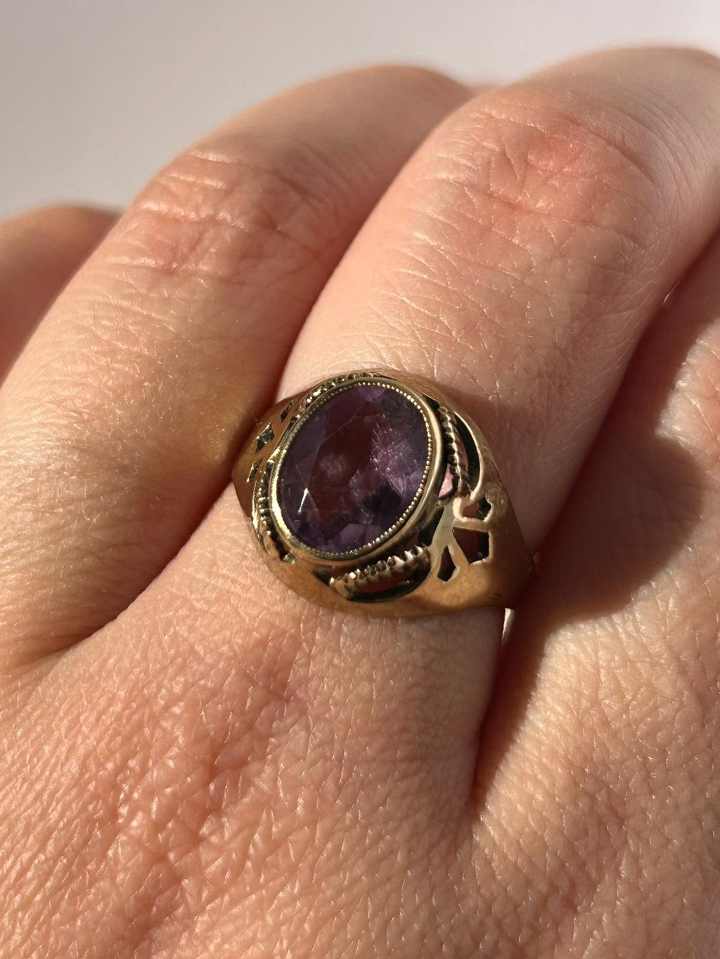 Anillo vintage de amatista en oro de 8 quilates con piedra de corte ovalado y hombros calados.